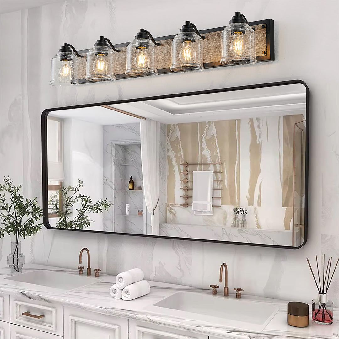 Multi-light wall sconce with clear glass shades, mounted above a bathroom mirror with greenery for a fresh look.