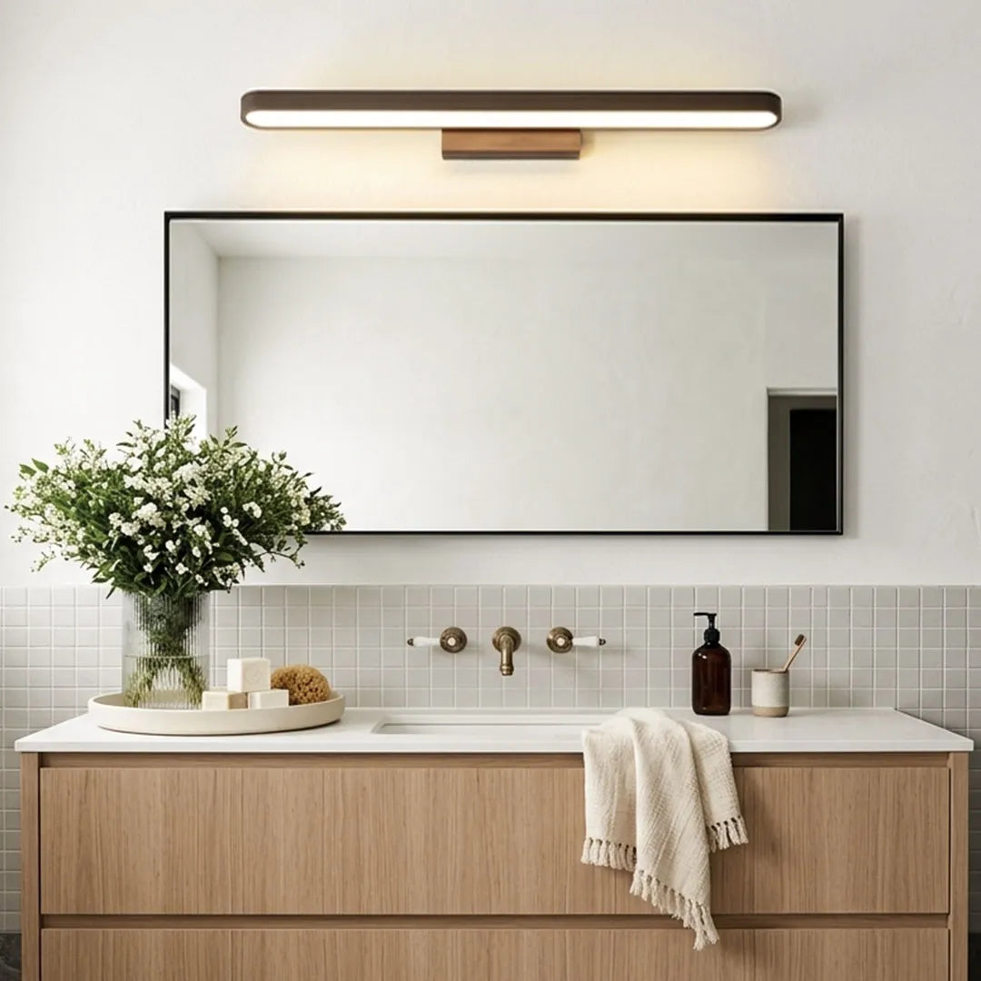 Bathroom vanity bar light above a rectangular mirror in a contemporary bathroom with a floating wood vanity.