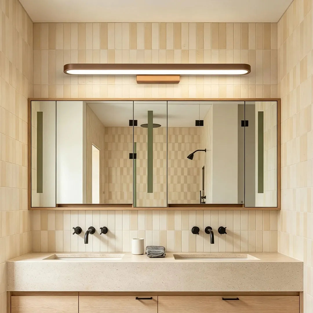 Bathroom vanity bar light installed above a wide mirror in a warm neutral bathroom with a double sink vanity.