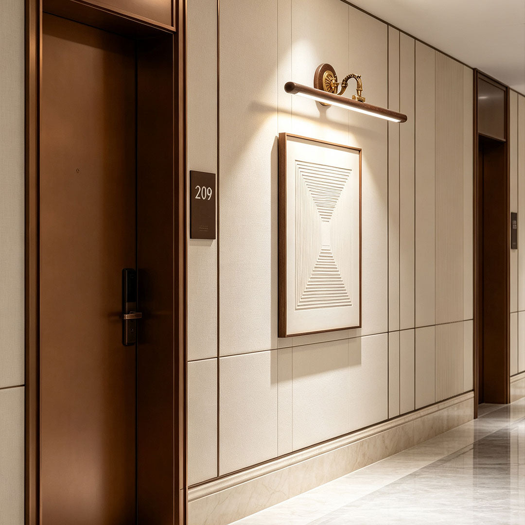 Bathroom vanity bar light fixtures installed above framed wall artwork in a modern hallway interior.