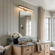 Bathroom vanity bar light mounted above a rectangular mirror in a bathroom with a wood vanity and marble countertop.