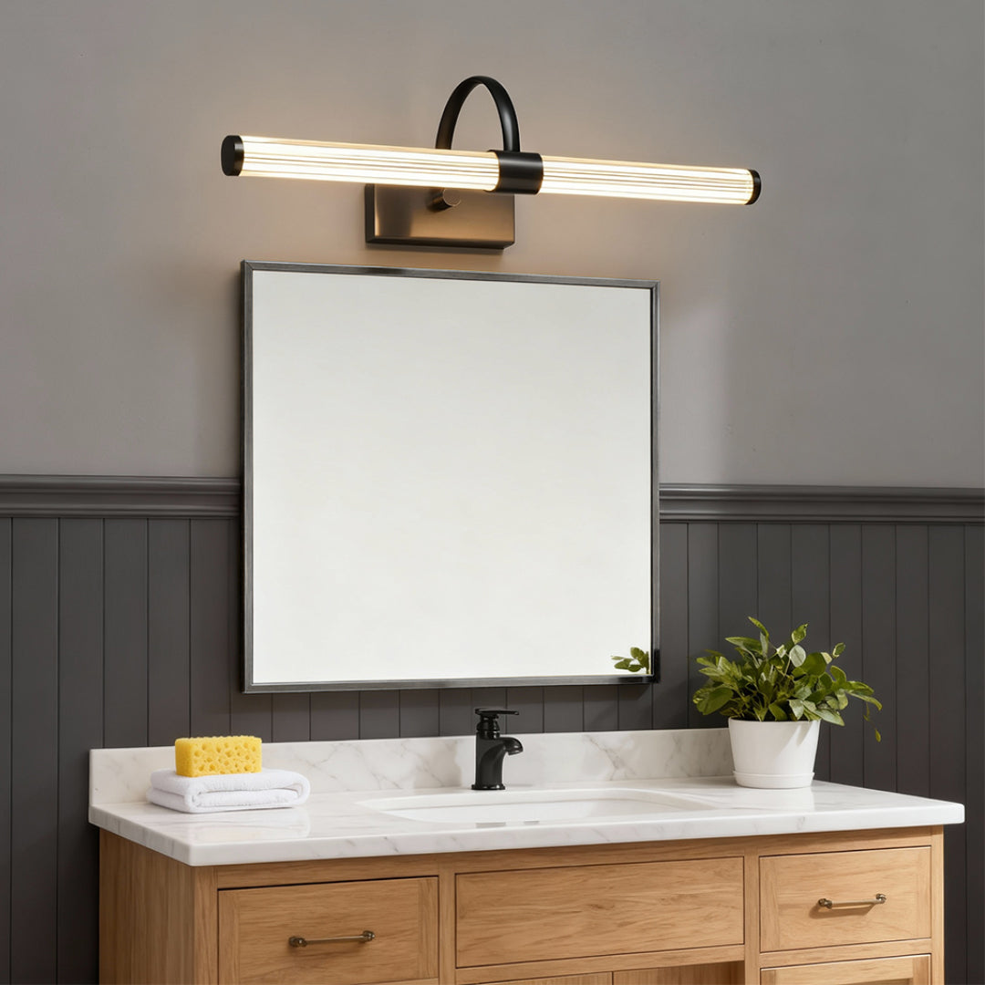 Bathroom vanity wall light installed above wooden vanity with white sink and framed mirror.