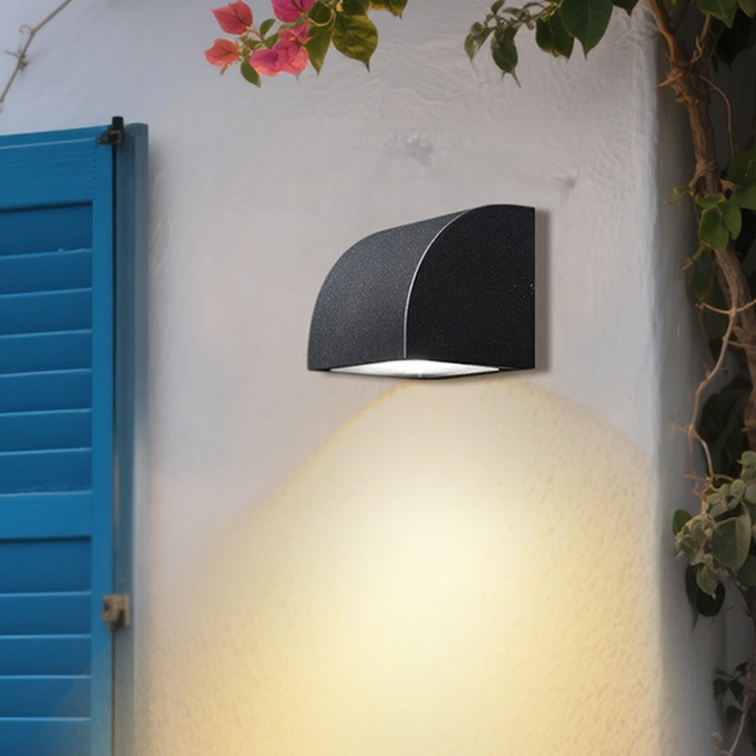 Traditional brass wall lantern with frosted glass shade mounted on stone exterior wall