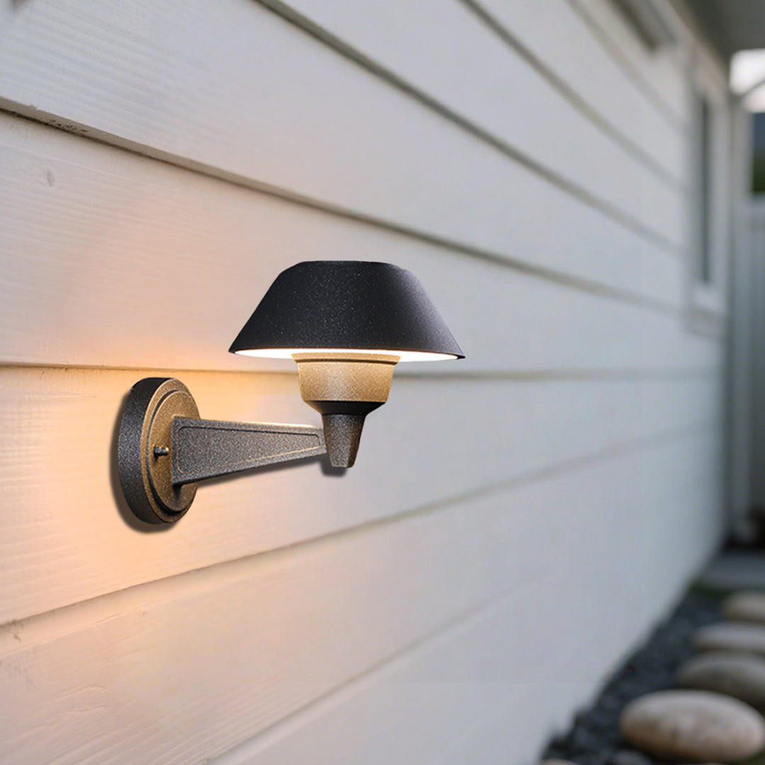Modern black dome wall light with extending arm illuminating brick exterior wall at dusk