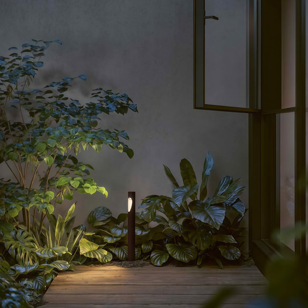Beachside landscape with silver garden bollard led lights illuminating plants near rocky shoreline.