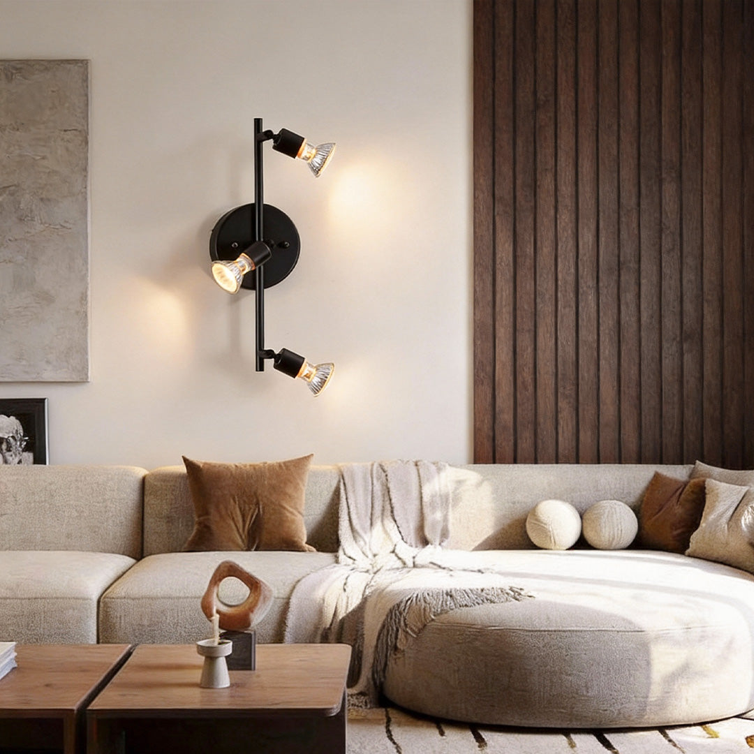 Black adjustable ceiling lights combined with wall-mounted fixtures, creating layered lighting in a modern lounge area.