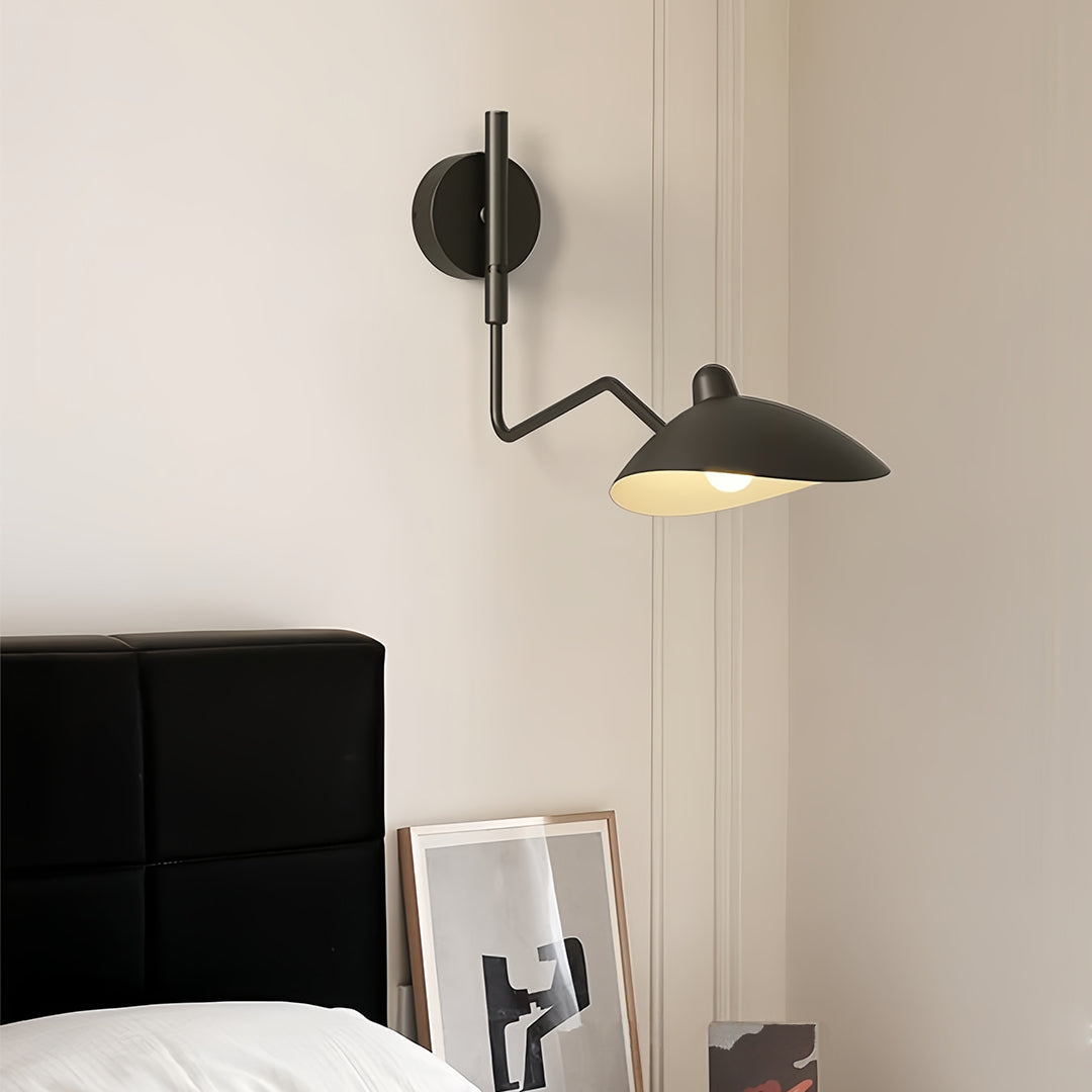Black articulated swing arm wall light with two adjustable heads, providing focused bedside reading light above a minimal headboard.