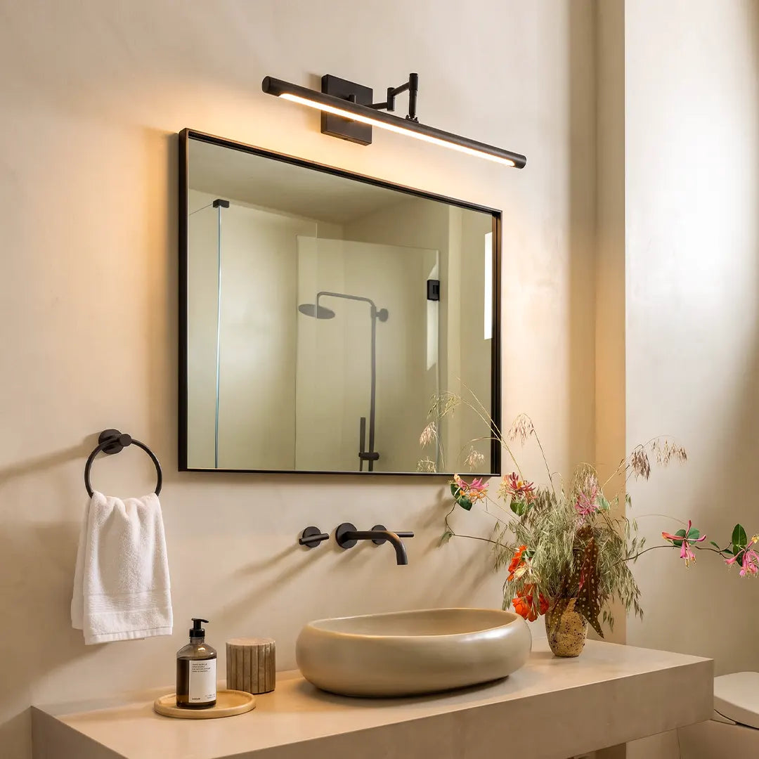 Black bar vanity light installed above a bathroom mirror with a vessel sink and modern black fixtures.