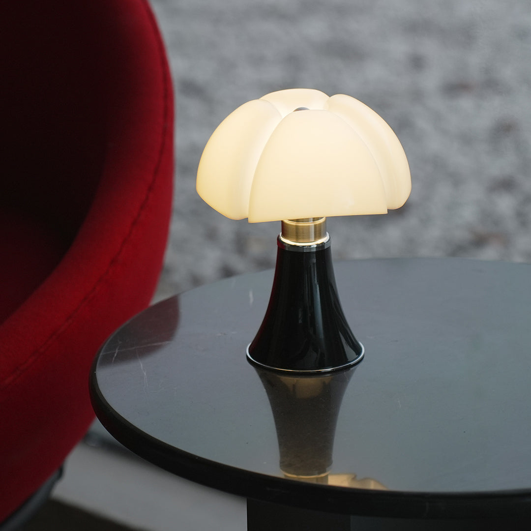 Black Bauhaus table lamp with white shade on red side table, modern decor.
