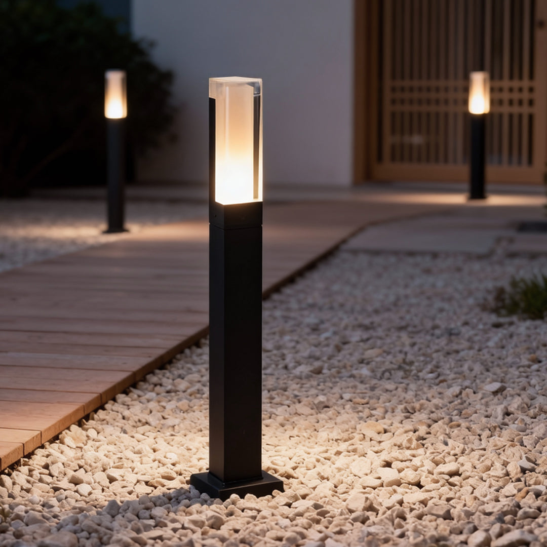 Black bollard light installed along a modern outdoor walkway at night