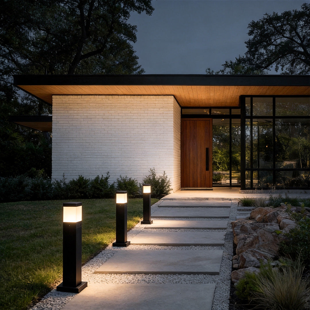 Black bollard lights commercial installation along a paved walkway leading to a contemporary building entrance.