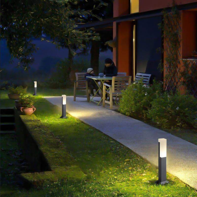 Black bollard lights illuminating garden pathway at night