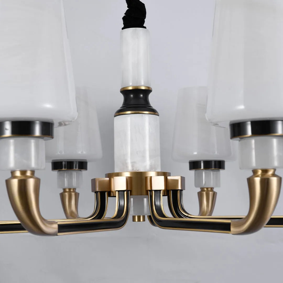 Close-up of black brass chandelier featuring curved brass arms and elegant white lamp shades.