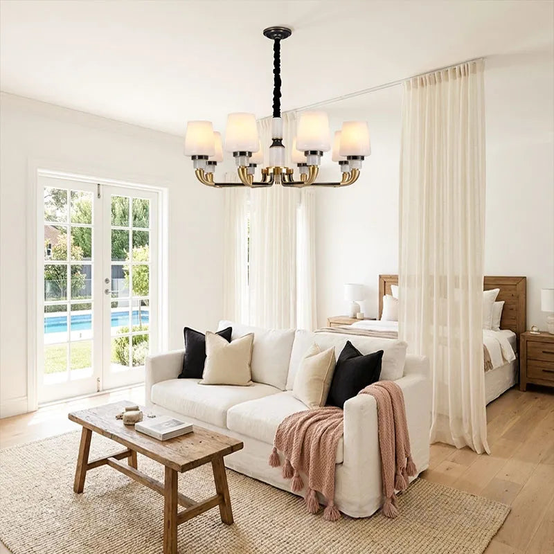 Black brass chandelier illuminating a modern living room with elegant curved arms and white shades.