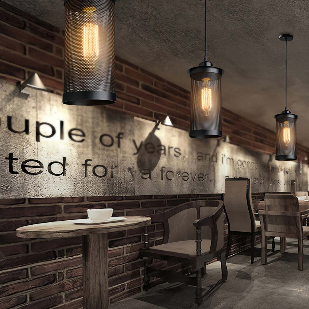Black cage retro industrial pendant lights hanging over a small wooden table against a textured brick and painted wall.