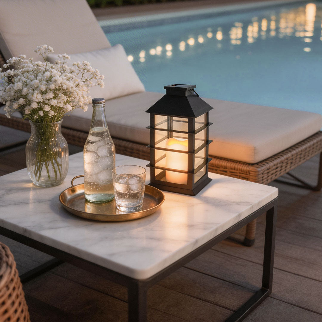 Black candlestick lantern on a marble pool table next to a drink tray and white flower vase.