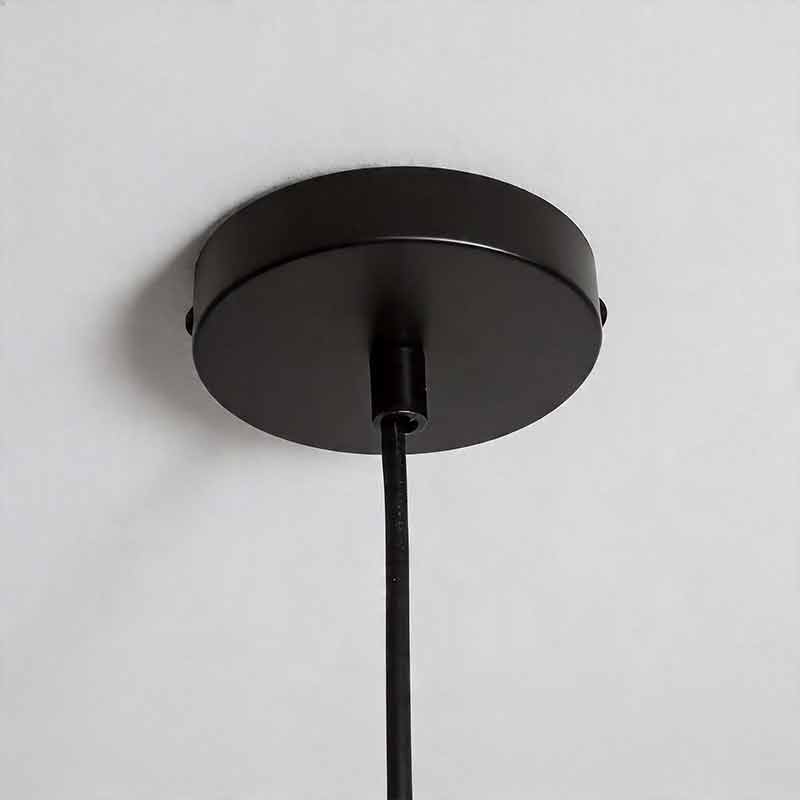Macro detail of the black ceiling canopy and cord for industrial style pendant light fixtures.