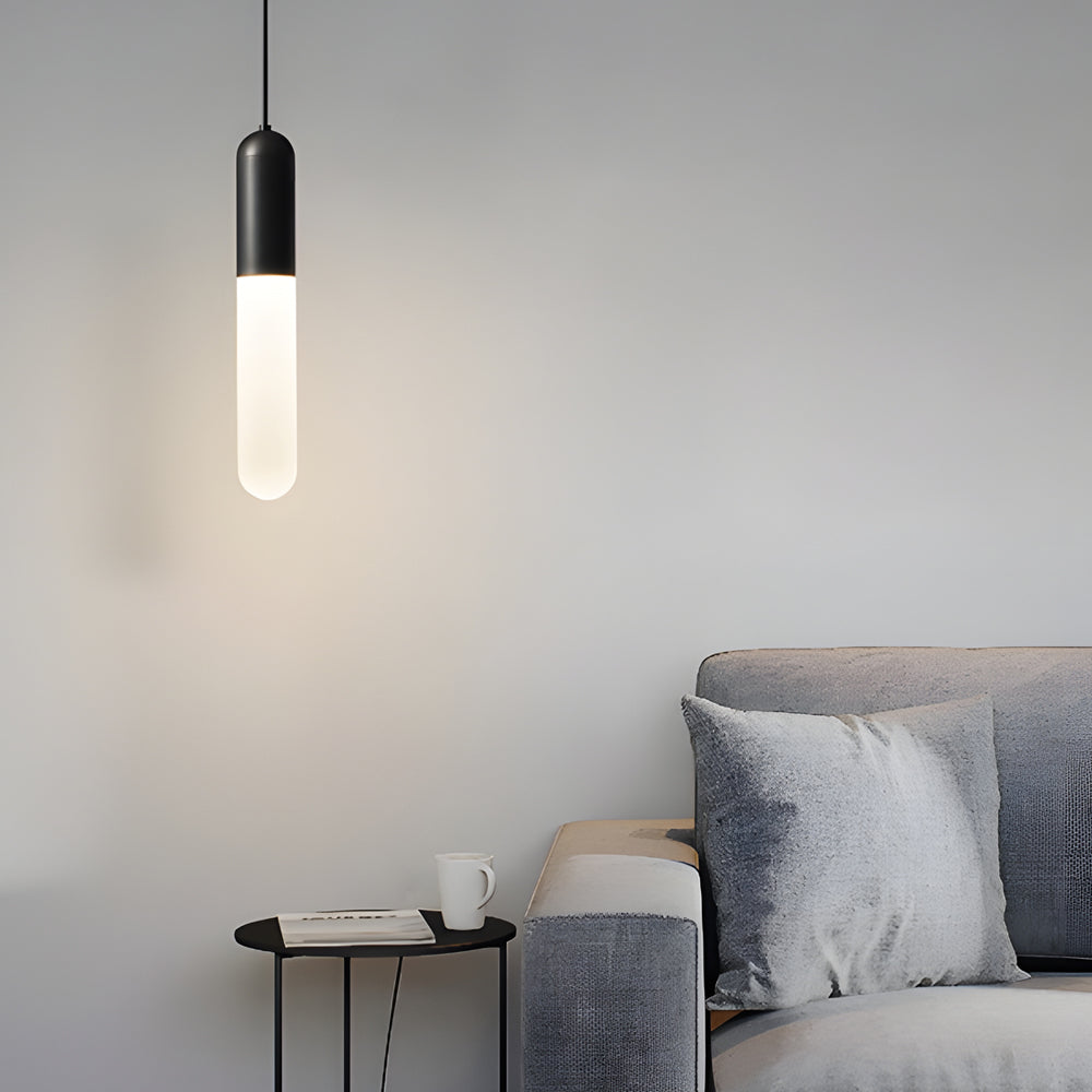 Minimalist black Capsule Pendant Light hanging in a modern living room beside a grey sofa.