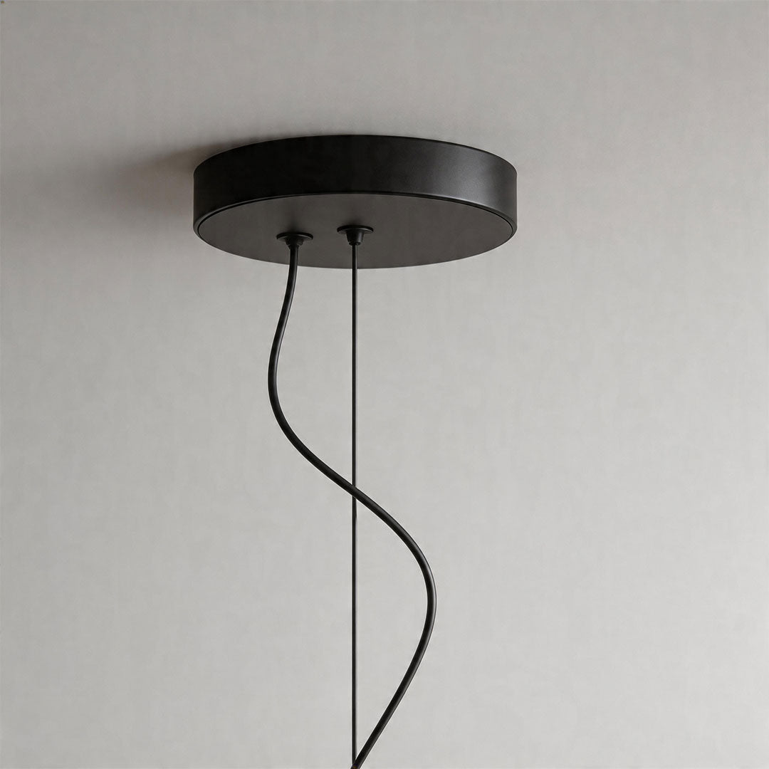 Black ceiling canopy and cord detail of modern chandelier fixture with minimalist design.