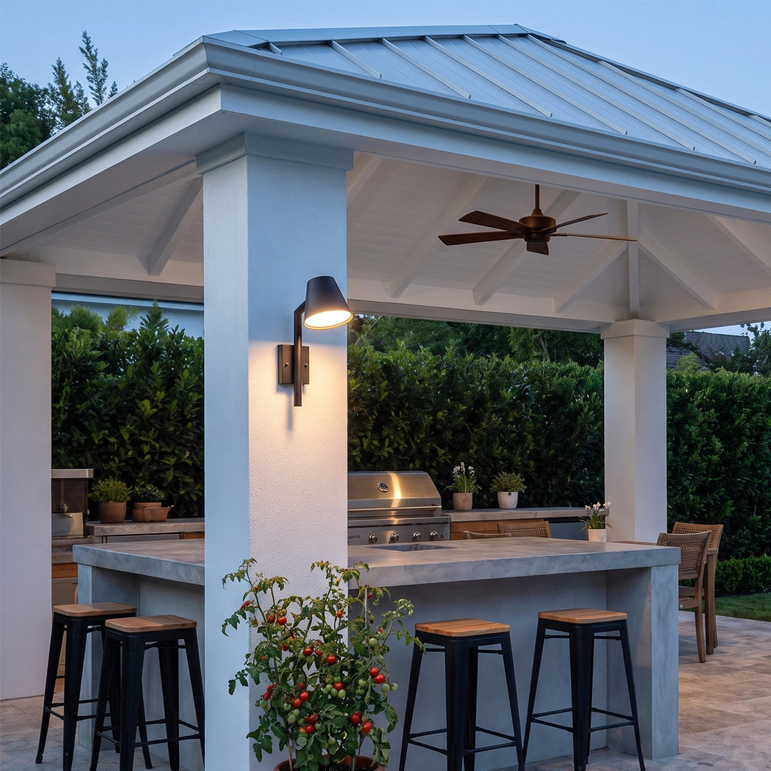 Black cone wall sconce mounted on an outdoor pavilion column beside a covered kitchen and bar area.