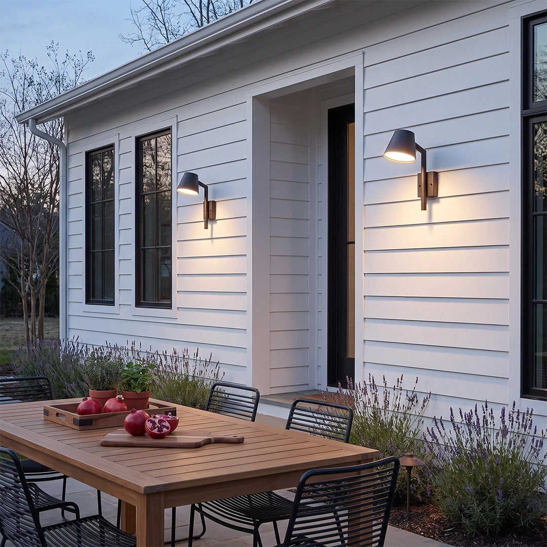 Black cone wall sconce installed along a white siding patio wall above an outdoor dining table.