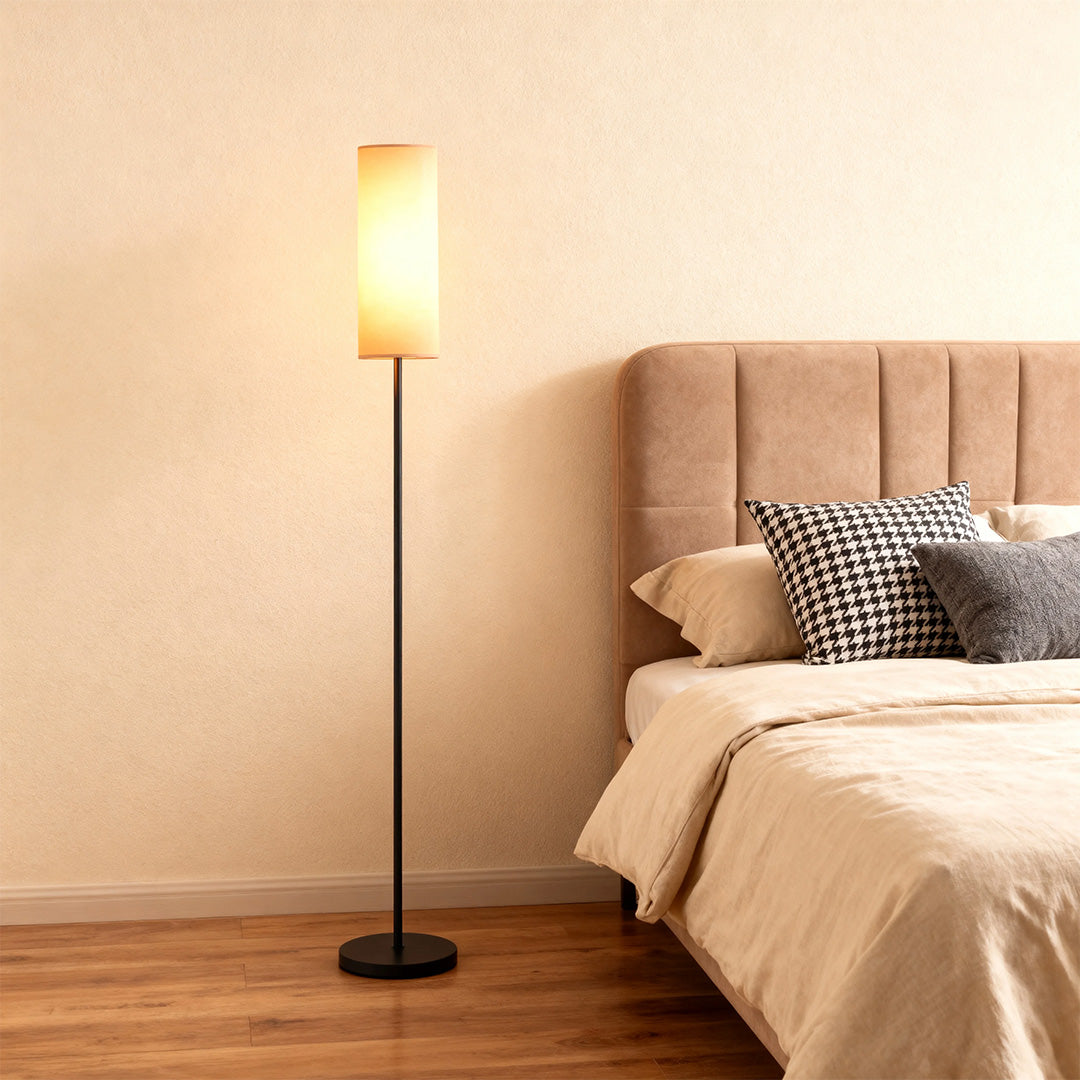 Black wrought iron floor lamps providing ambient lighting beside bed with blush upholstered headboard