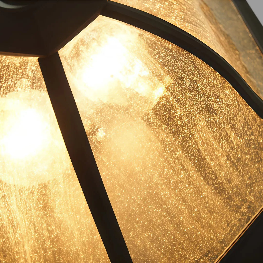 Close-up of a black flush mount light fixture with textured amber glass and warm illumination.