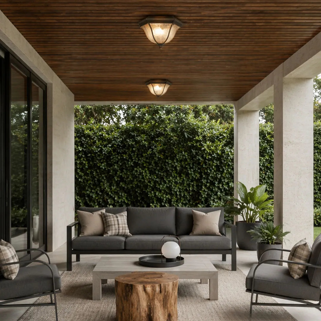 Black flush mount light fixture mounted on a wood ceiling above a covered outdoor lounge.