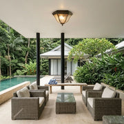 Black flush mount light fixture illuminating a covered poolside patio with woven outdoor seating.