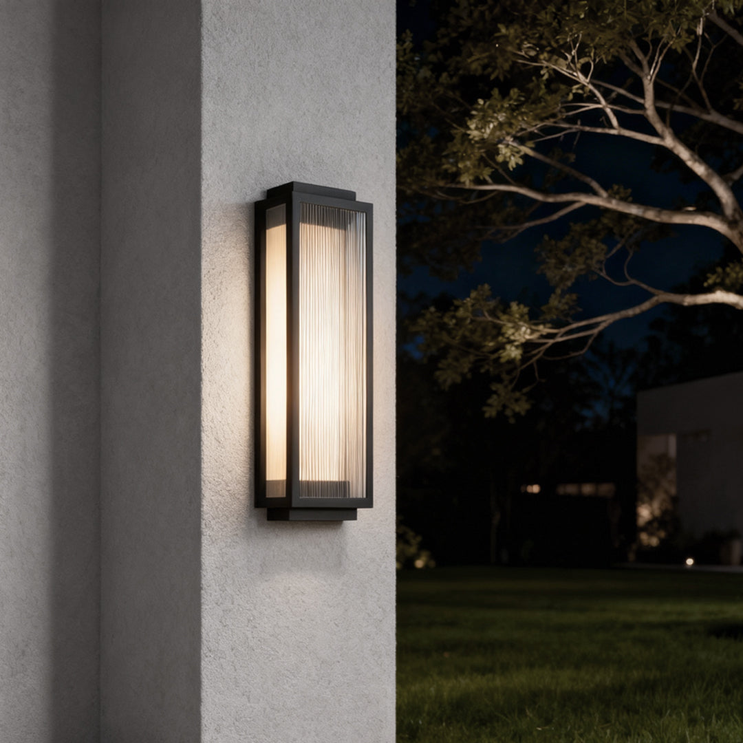 Black-framed reeded glass light fixture providing soft illumination for a modern exterior wall.