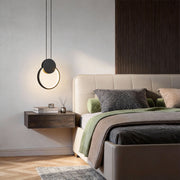 Black geometric pendant light installed beside bed as modern bedroom lighting.