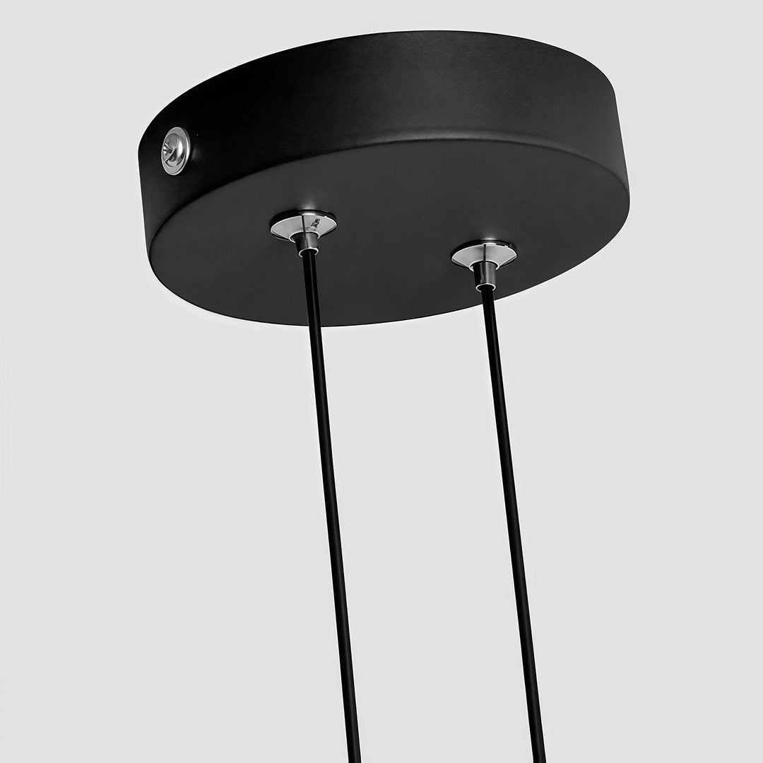 Close-up of black geometric pendant light ceiling canopy and suspension cords.