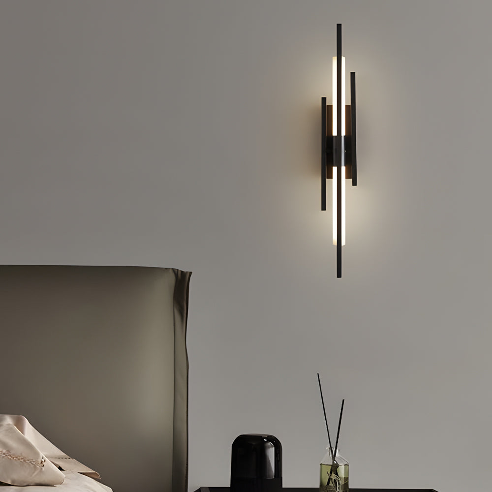 Black and gold vertical tube wall sconce on modern gray wall.