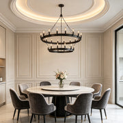 Black iron chandelier hanging above a modern round dining table in a luxurious contemporary interior.