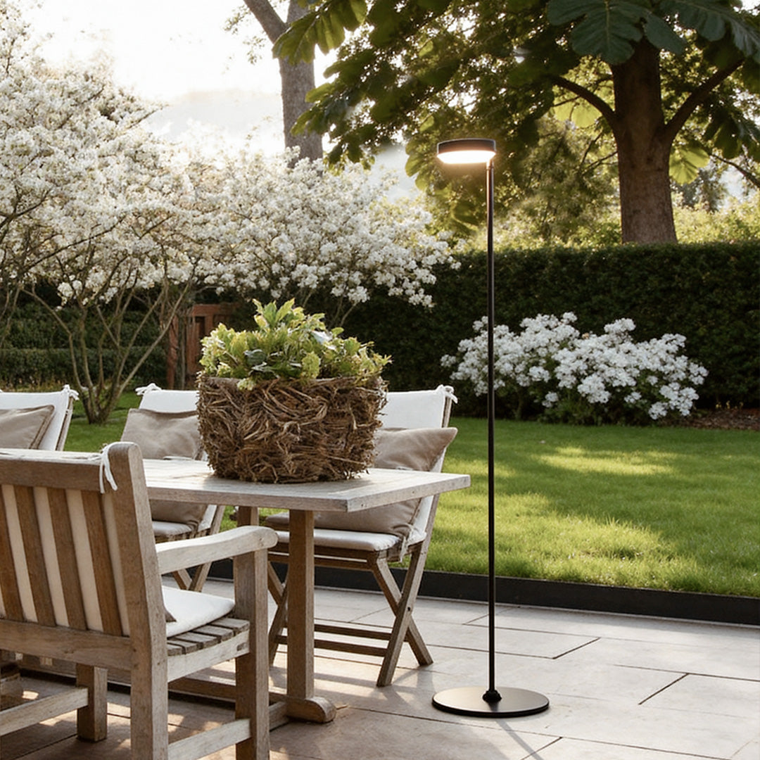 Black lamp floor with a minimalist design, illuminating an outdoor dining table.