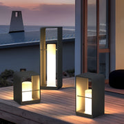 Black lantern outdoor light with modern geometric design, placed on wooden deck near pool at dusk.