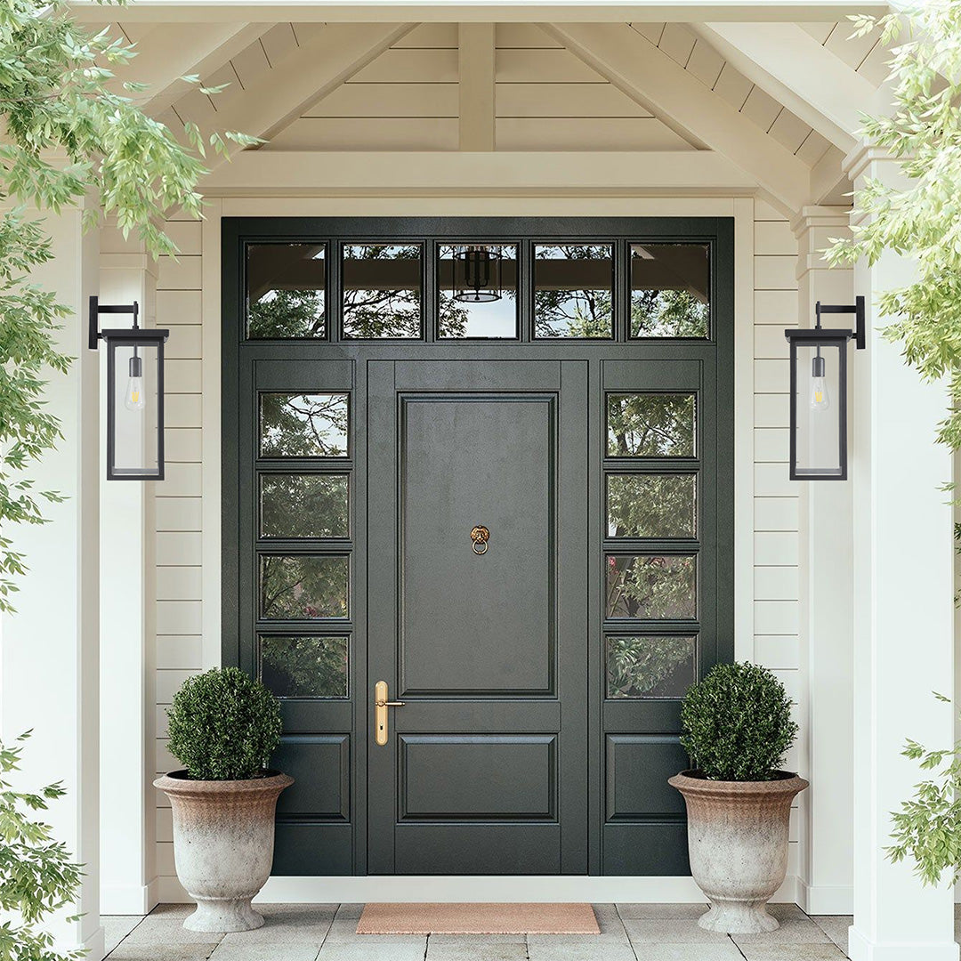 Black exterior lantern wall light mounted above a white door, providing elegant and functional outdoor lighting.