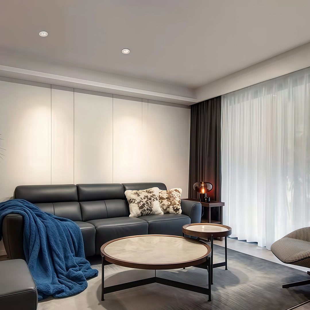 Sleek living room featuring a black leather sofa and a textured wall lit by multiple modern spotlights.