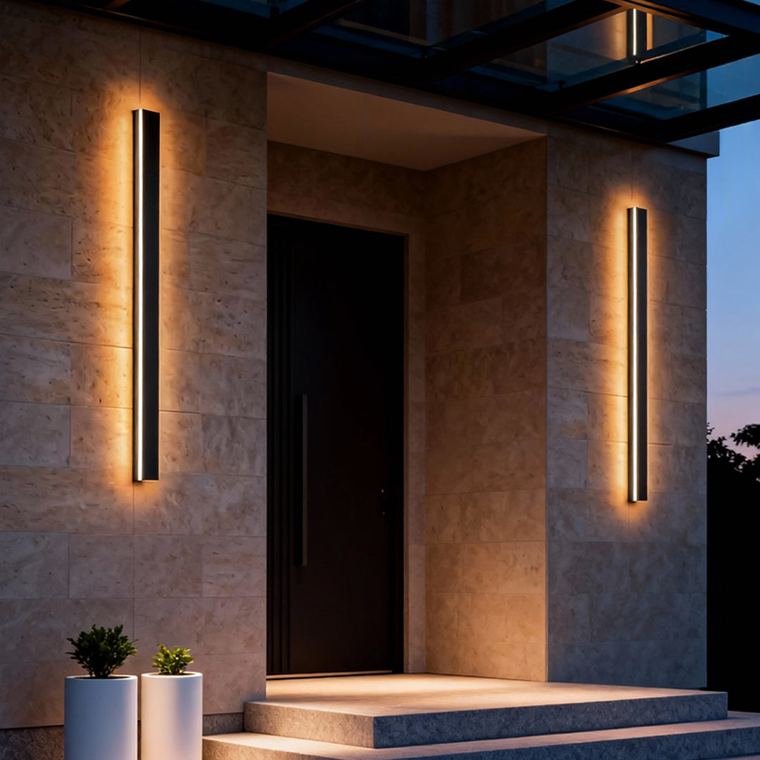 Black linear wall light illuminating a modern outdoor corridor with linear glow.