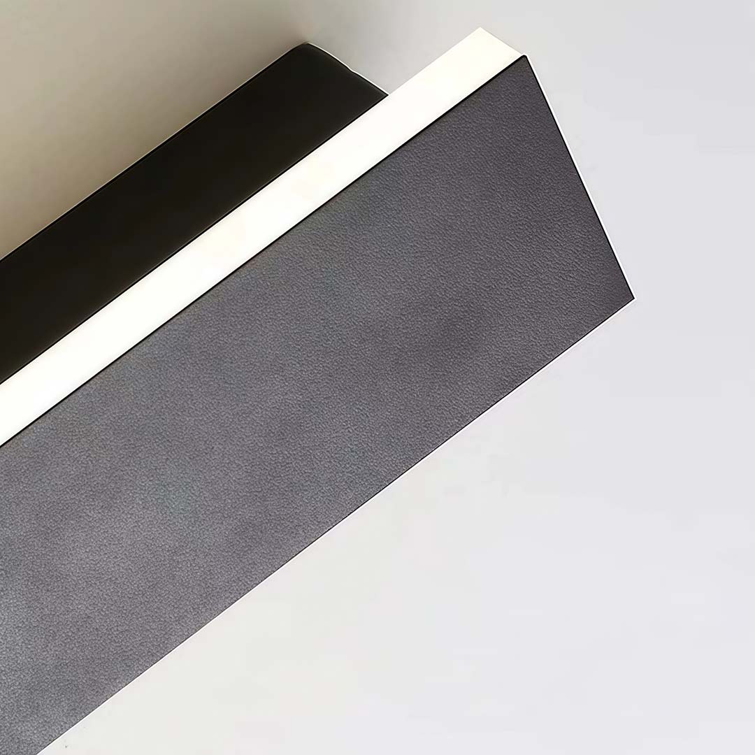 Black linear wall sconce with a close-up of its illuminated linear structure.