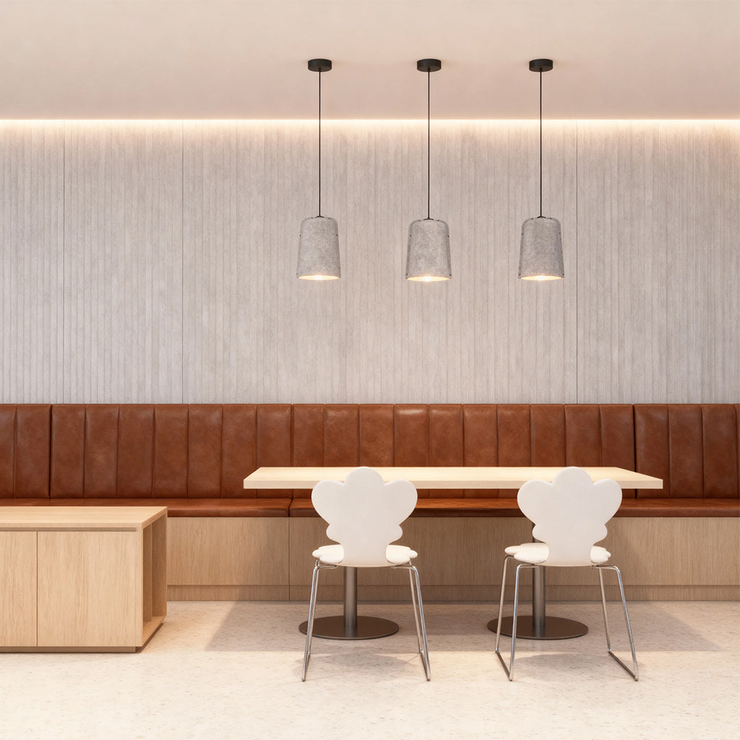 A linear arrangement of three black mesh-style adjustable pendant light fixtures providing focused lighting above a modern cafe bench seating area.