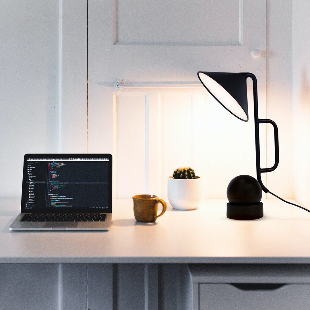 Black metal USB rechargeable table lamp illuminating modern workspace with laptop setup