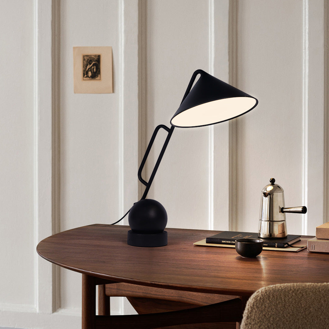 Black metal desk lamp with USB rechargeable base positioned on wooden table in natural setting