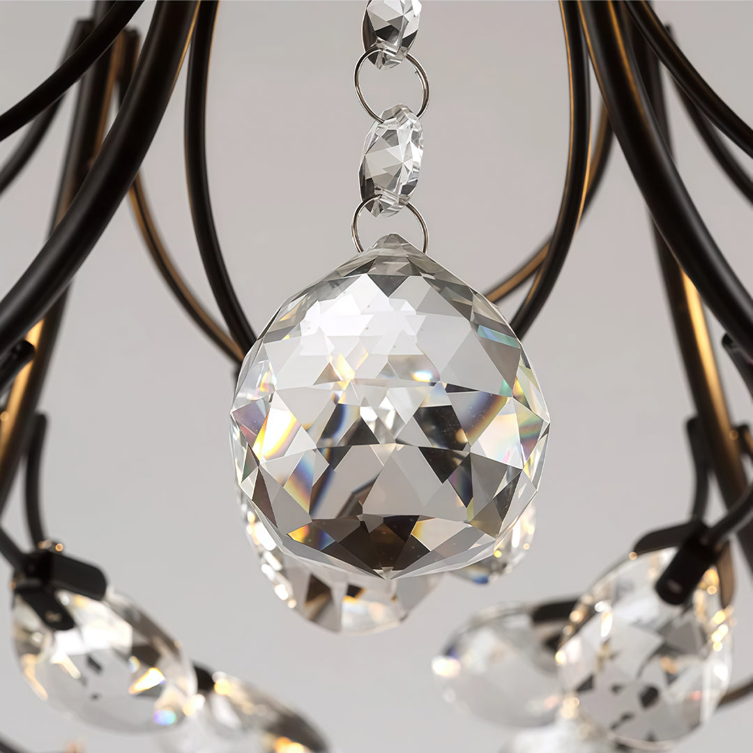Close-up of a faceted crystal drop hanging from a black modern branch chandelier frame.