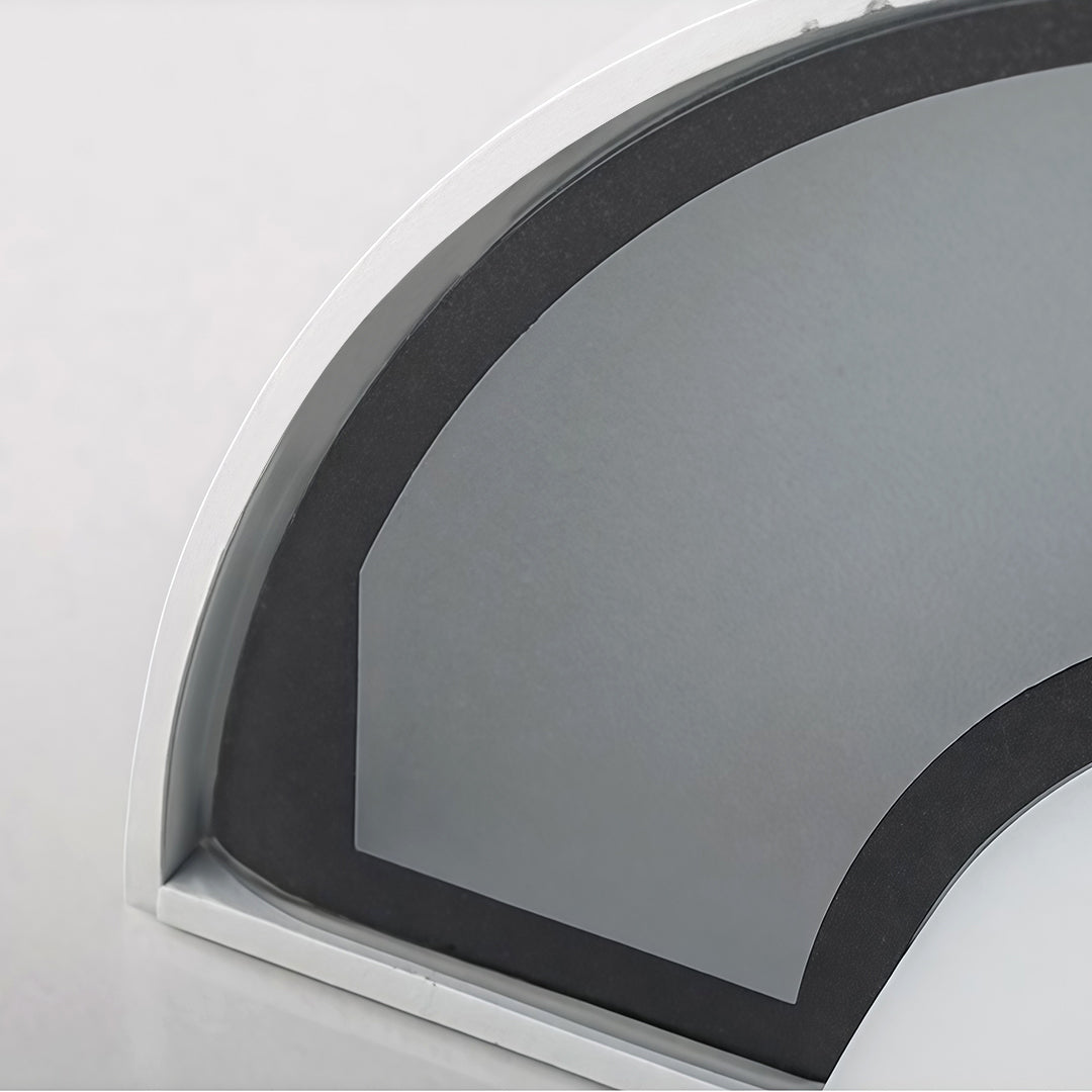 Mushroom wall light in black, casting a stylish and warm light on an urban stone wall in the evening.