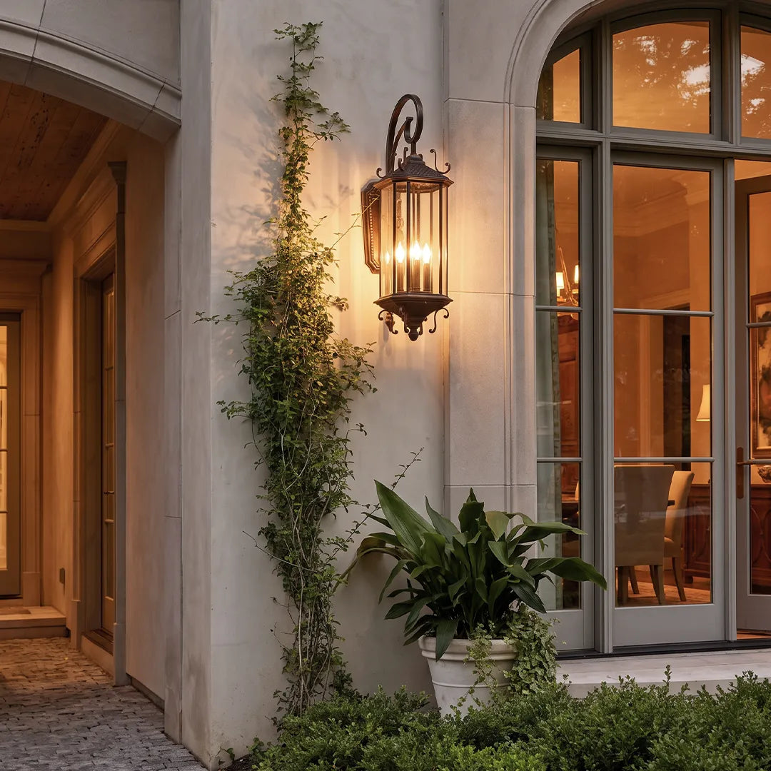 Black outdoor lantern sconce installed beside an arched glass doorway, adding elegant illumination to a covered front porch.