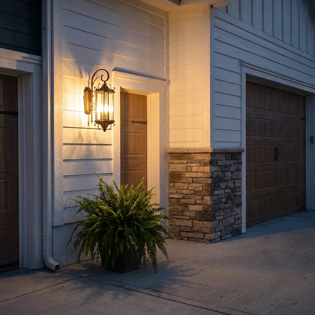 Black outdoor lantern sconce mounted near a garage entry, providing warm exterior lighting against white siding and stone accents.