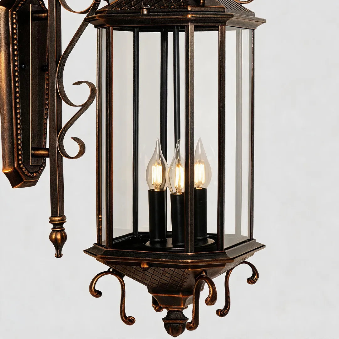 Black outdoor lantern sconce close-up showing the clear glass frame and candle-style bulbs inside the classic lantern body.
