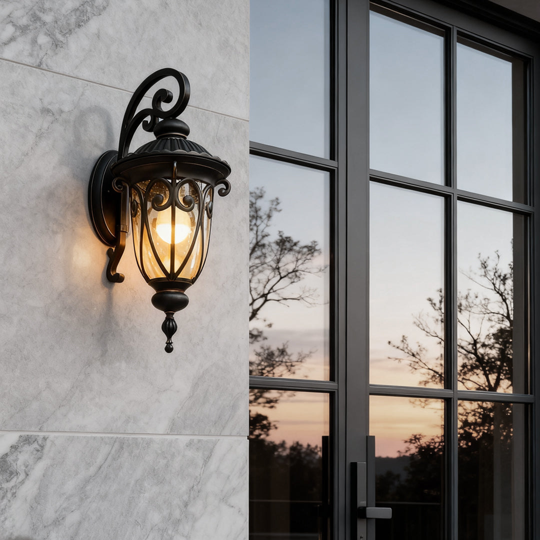 Black outdoor lantern sconce installed on a marble wall, enhancing the exterior with elegant lighting.