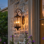 Black outdoor lantern sconce mounted on a stone exterior wall, bringing classic charm and warm entry lighting to the home.